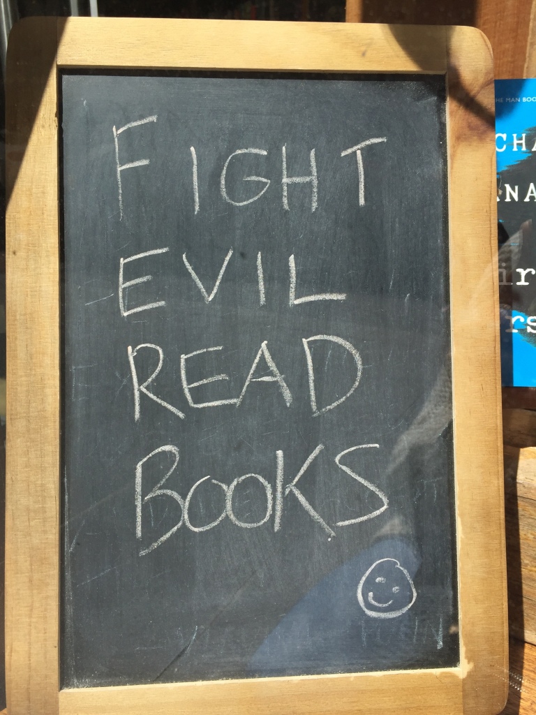 A chalkboard with these words written in chalk: FIGHT EVIL, READ BOOKS